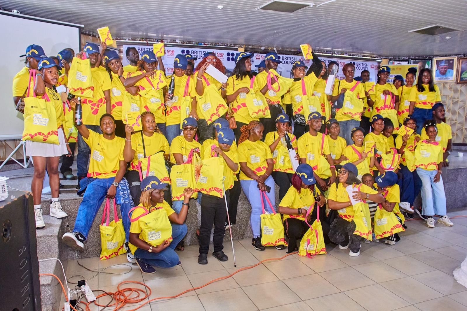A large group of ENDIP programme participants posing with branded bags at an enterprise event